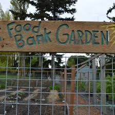 Wooden sign reading 'Food Bank Garden' in front of a garden with plants and trees
